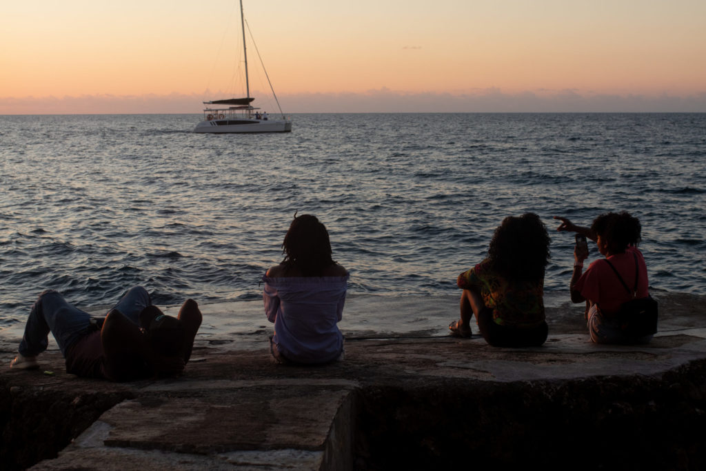 On BIPOC Mental Health Awareness Month and stigma. A group of people sitting by the sea at sunset.