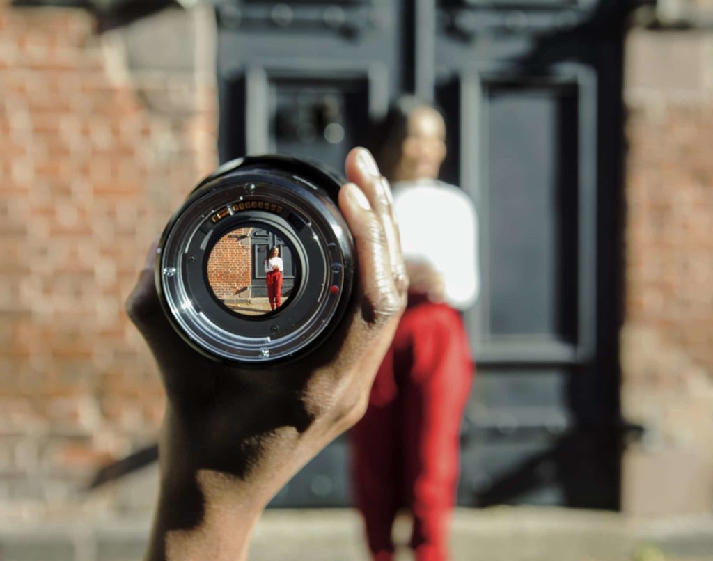 Wellness culture and its unfair burden. A picture of a woman standing outside, seen through a lens held by someone out of view.