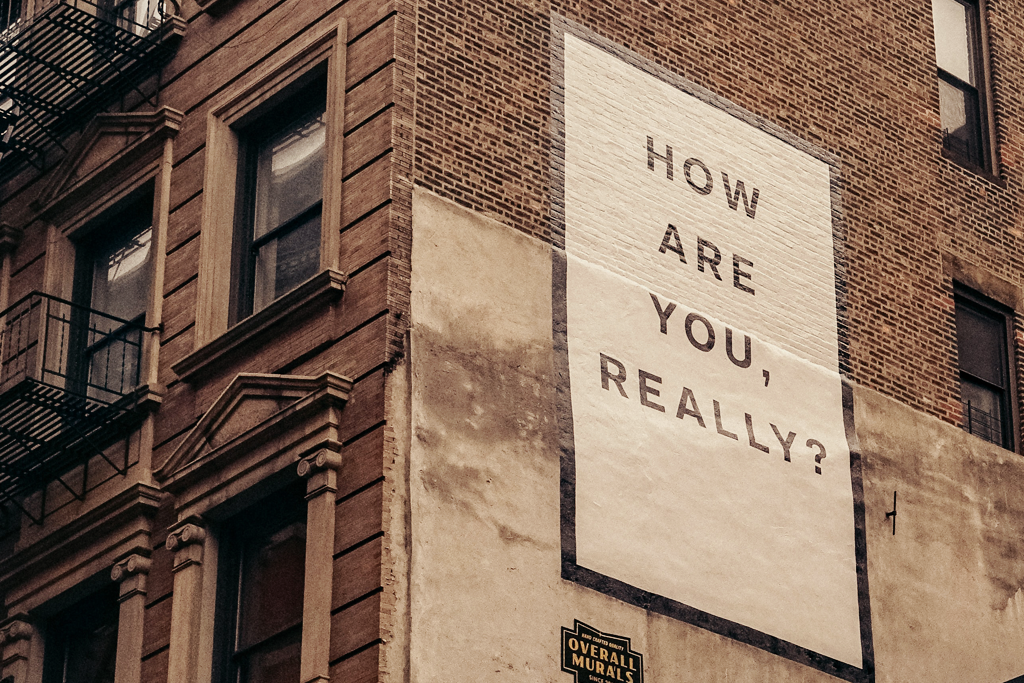 Understanding our emotions. A picture of the side of a building, showing a painted mural that says "How are you, really?"